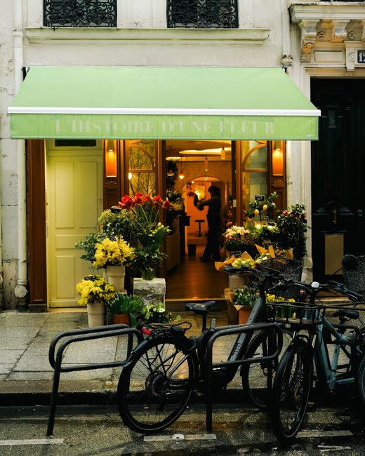 A vibrant display of fresh floral arrangements at a flower shop, featuring bouquets wrapped in colorful paper and arranged in various vases and baskets. The arrangement includes bright yellow sunflowe